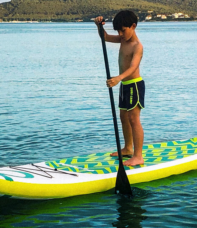 Un bambino si cimenta in un tipico Allenamento Estivo con il SUP